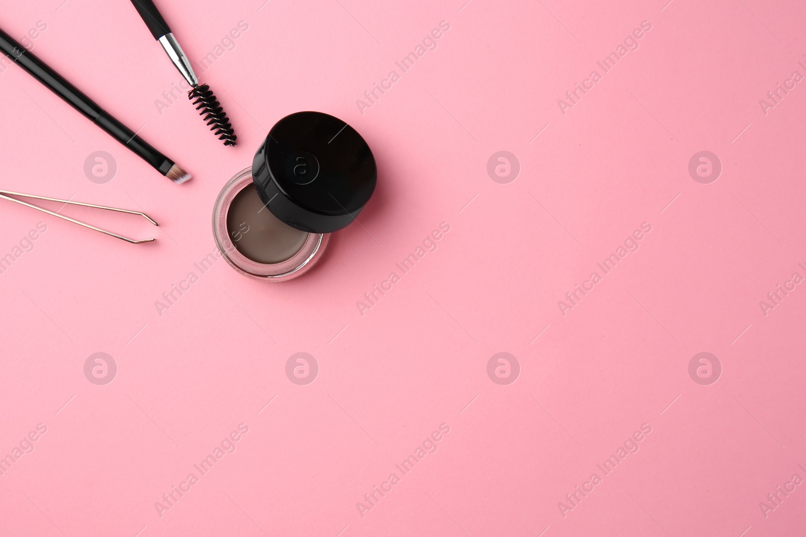 Photo of Eyebrow pomade with henna effect and professional tools on pink background, flat lay. Space for text