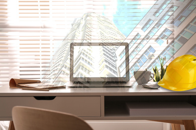 Image of Engineer workplace with laptop and modern building. Double exposure