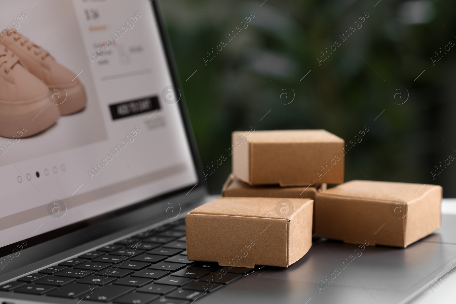Photo of Online store. Small parcels on laptop, closeup. Space for text