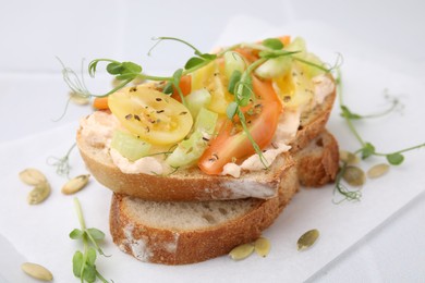 Photo of Tasty vegan sandwich with tomatoes, celery and microgreens on white table, closeup