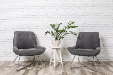 Room interior with modern chairs and table near white brick wall