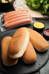 Photo of Different tasty ingredients for hot dog on dark table