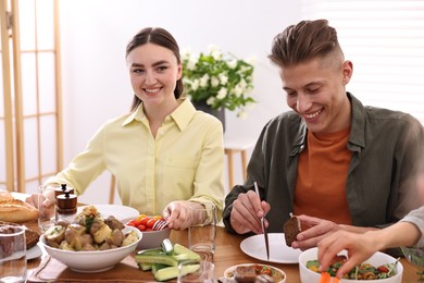 Friends eating vegetarian food at wooden table indoors