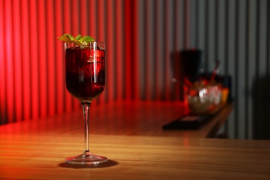 Photo of Glass of delicious cocktail with vodka on wooden counter in bar. Space for text