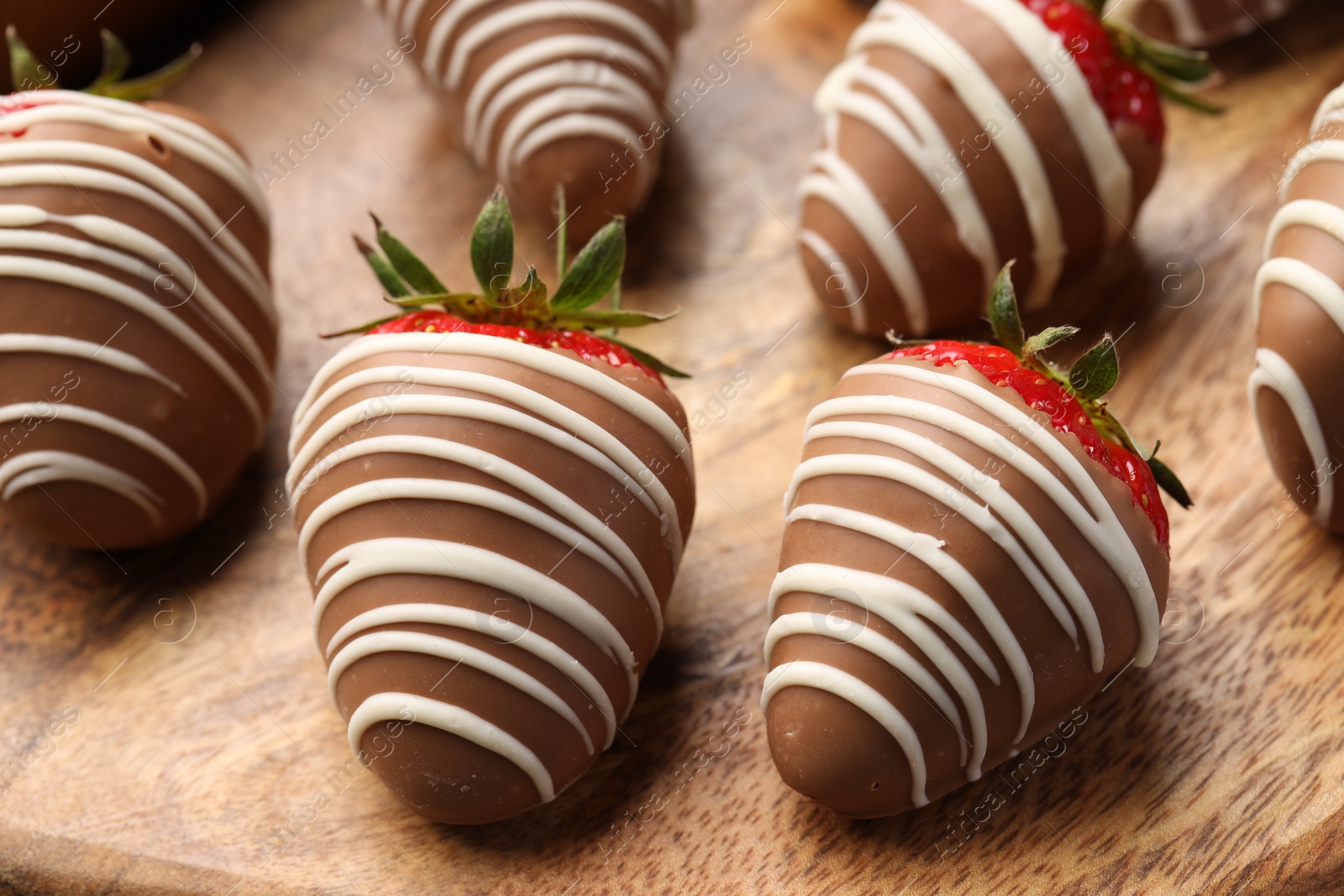 Photo of Delicious chocolate covered strawberries on wooden board, closeup