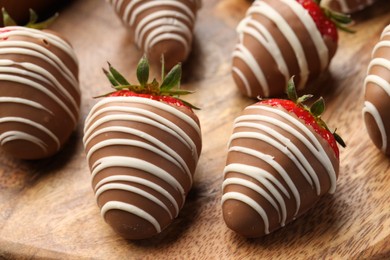 Photo of Delicious chocolate covered strawberries on wooden board, closeup