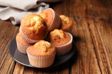 Photo of Delicious sweet muffins on wooden table, closeup. Space for text
