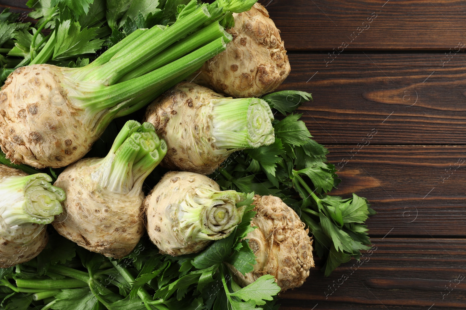 Photo of Fresh raw celery roots on wooden table, flat lay. Space for text