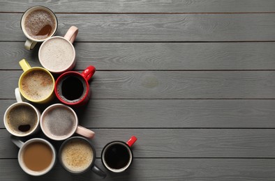 Many different cups with aromatic coffee on grey wooden table, flat lay. Space for text