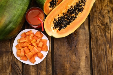 Photo of Flat lay composition with fresh juicy papayas on wooden table, space for text