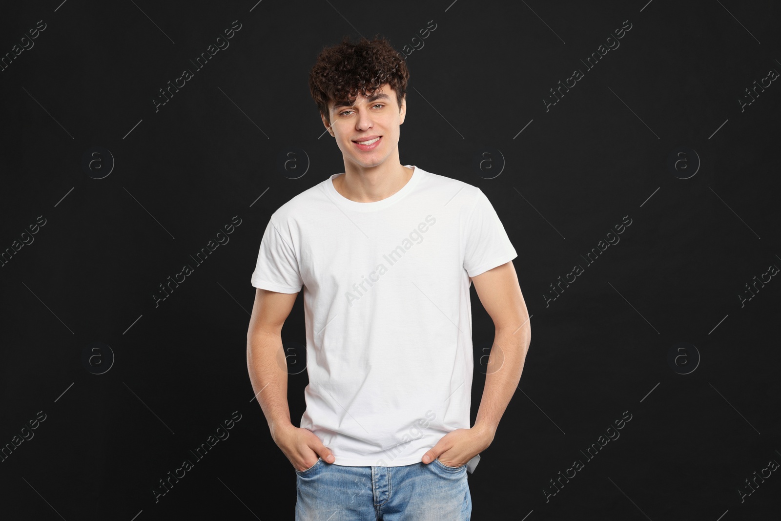 Photo of Man wearing white t-shirt on black background. Mockup for design