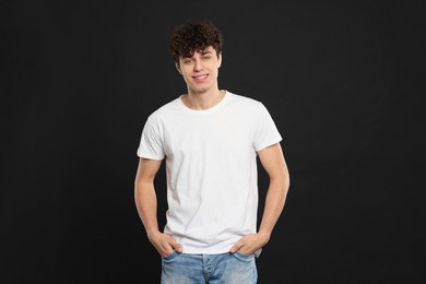 Man wearing white t-shirt on black background. Mockup for design