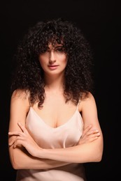 Photo of Beautiful young woman with long curly hair on black background