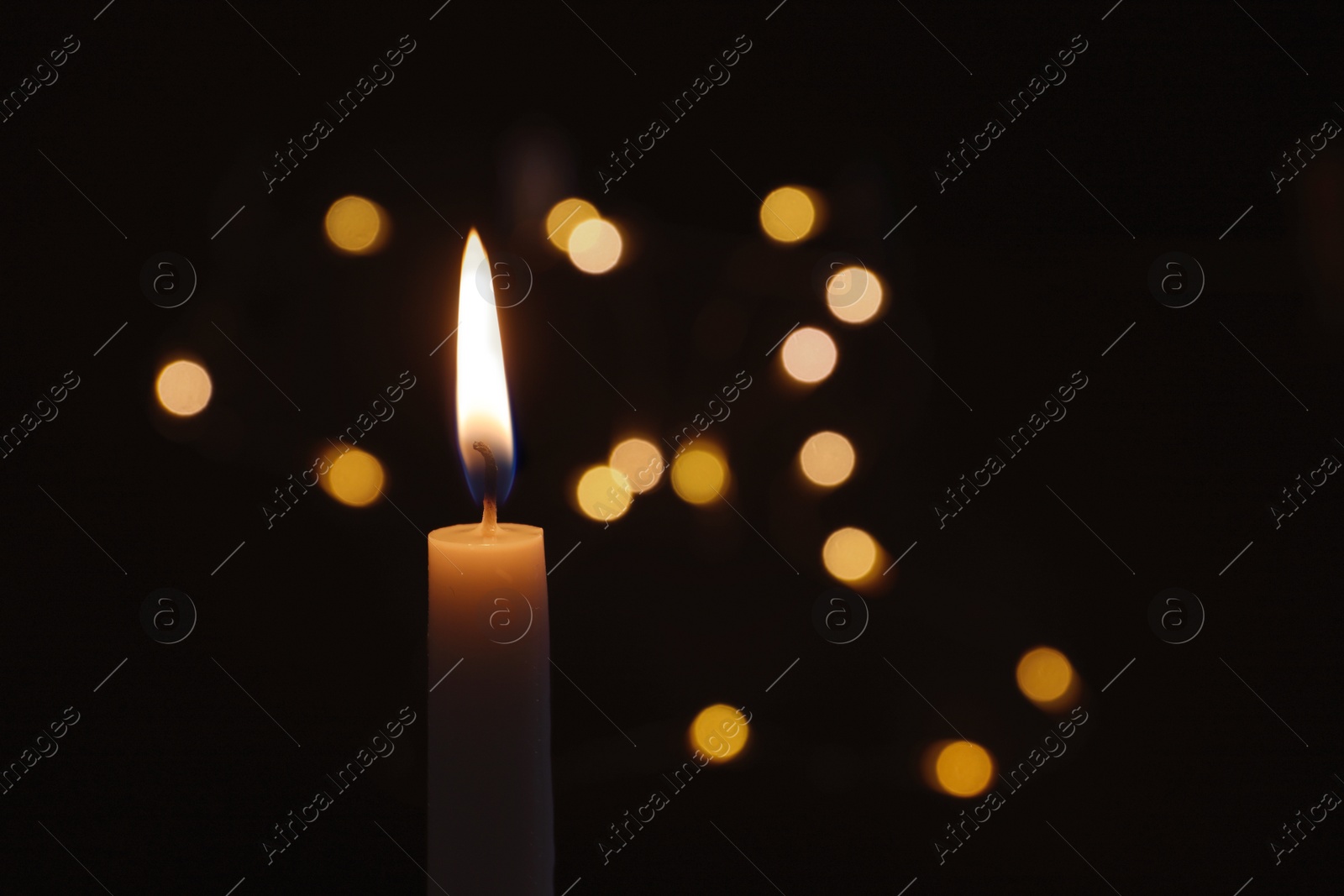 Photo of Wax candle burning on blurred background, closeup