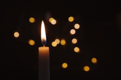 Photo of Wax candle burning on blurred background, closeup