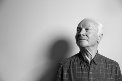 Portrait of elderly man on light background, space for text. Black and white effect