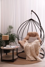 Photo of Comfortable place for rest with hanging chair near window in room