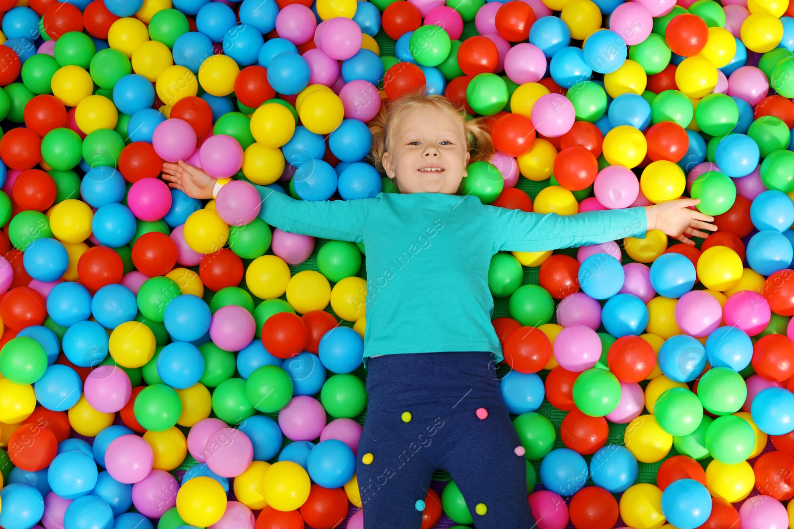 Photo of Cute child playing in ball pit indoors