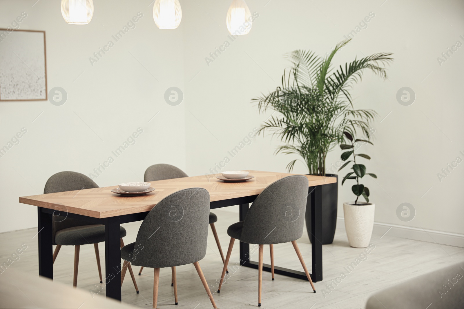 Photo of Stylish wooden table and chairs in light room. Modern interior design