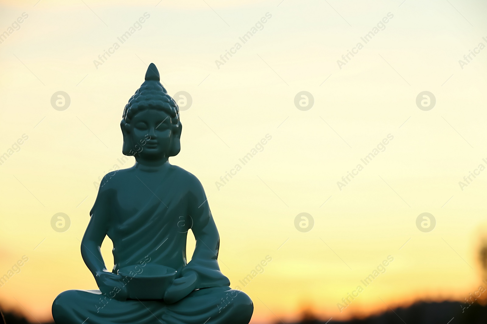 Photo of Decorative Buddha statue outdoors at sunset. Space for text
