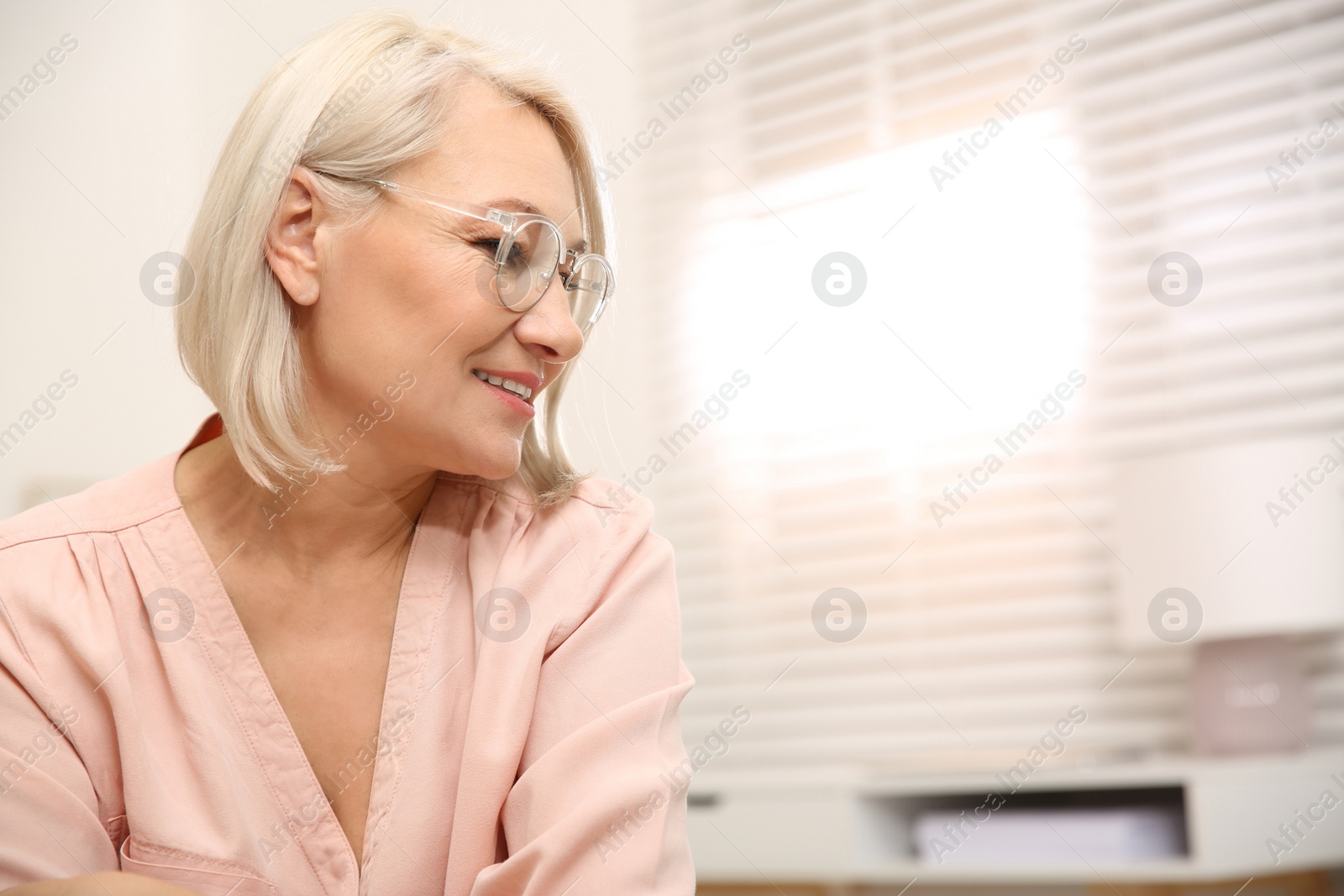 Photo of Beautiful mature woman in glasses at home. Space for text