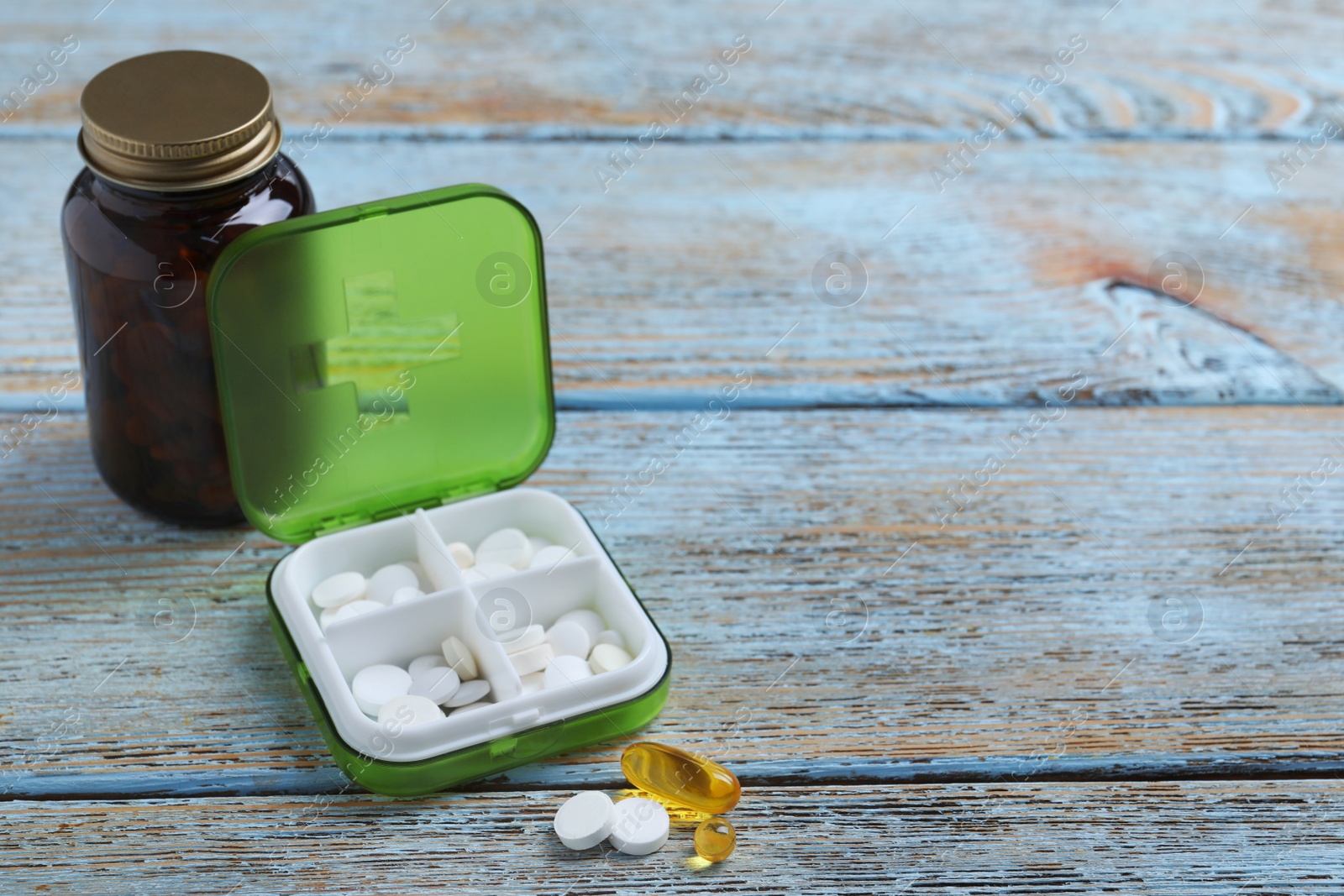 Photo of Pill box with medicaments on wooden table. Space for text