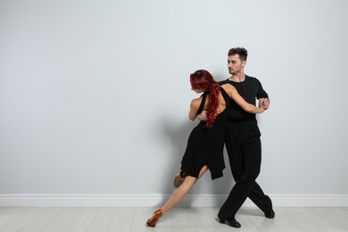 Beautiful young couple dancing near light wall