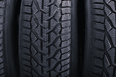 Photo of Black car tires as background, closeup. Auto store