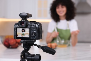 Food blogger recording video in kitchen, focus on camera