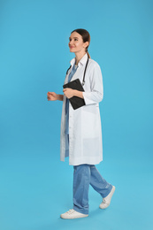 Doctor with clipboard and stethoscope walking on blue background