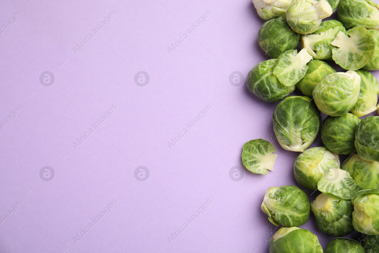 Photo of Fresh Brussels sprouts on violet background, flat lay. Space for text
