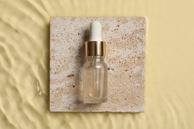 Bottle of cosmetic serum and water on beige background, top view