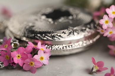 Beautiful Forget-me-not flowers and pocket watch on grey table, closeup