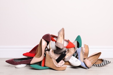 Heap of different shoes on floor against light wall