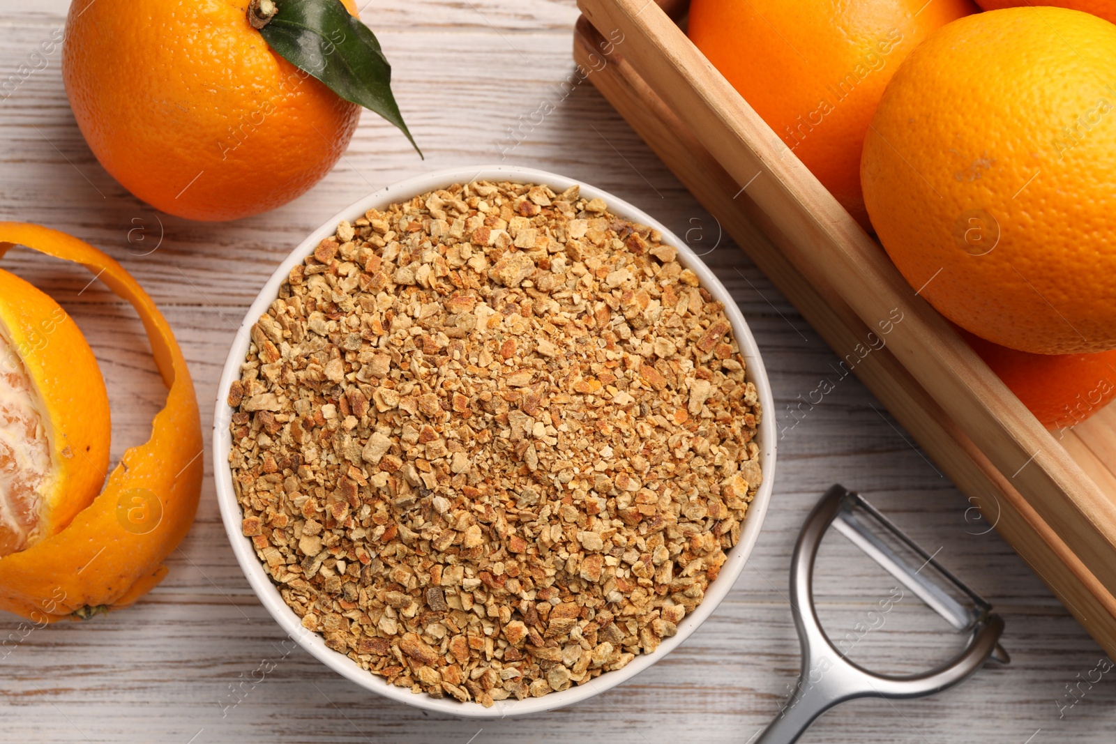 Photo of Bowl with dried orange seasoning zest and fruits on white wooden table, flat lay