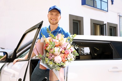 Photo of Delivery man with beautiful flower bouquet near car outdoors