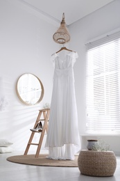 Photo of Beautiful wedding dress, shoes and flowers in room