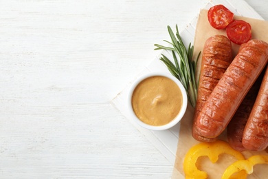 Flat lay composition with delicious grilled sausages on white wooden table, space for text. Barbecue food