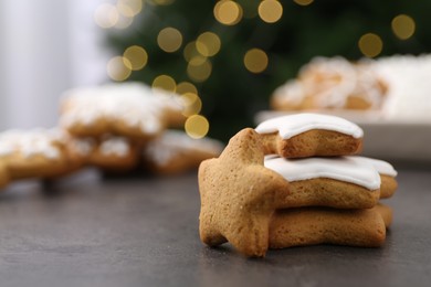 Photo of Decorated cookies on grey table against blurred Christmas lights, closeup