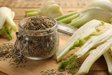 Photo of Fennel seeds in jar and fresh vegetables on wooden table, closeup