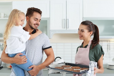 Young woman treating her family with homemade oven baked cookies in kitchen