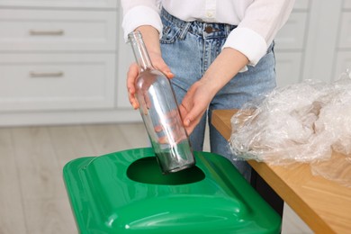 Woman separating garbage at table indoors, closeup