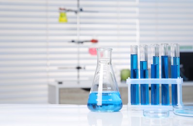 Photo of Laboratory analysis. Different glassware with blue liquid on white table indoors