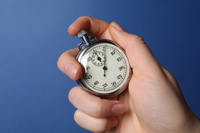 Woman holding vintage timer on blue background, closeup