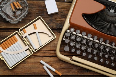 Photo of Flat lay composition with stylish cigarette case and vintage typewriter on wooden table