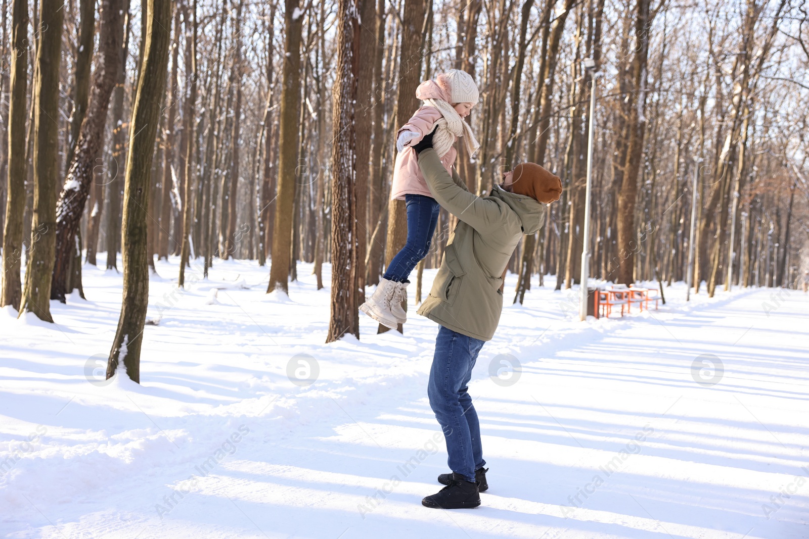 Photo of Family time. Father playing with his daughter in snowy forest