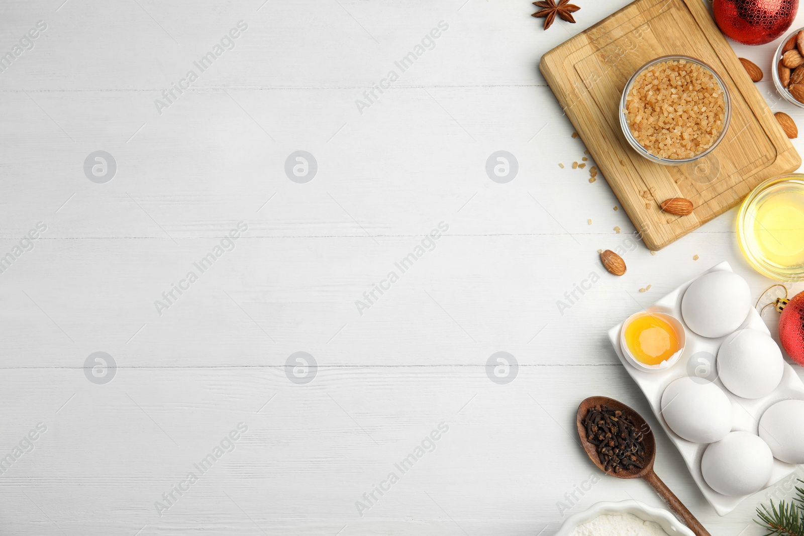 Photo of Flat lay composition with ingredients for traditional Christmas cake on white wooden table. Space for text