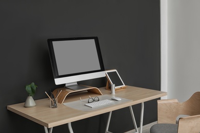 Photo of Modern workplace interior with computer on table. Space for text