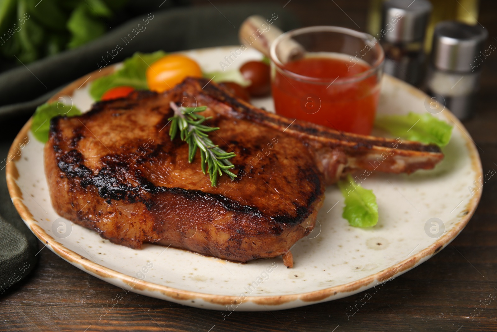 Photo of Tasty grilled meat, rosemary and marinade on wooden table, closeup