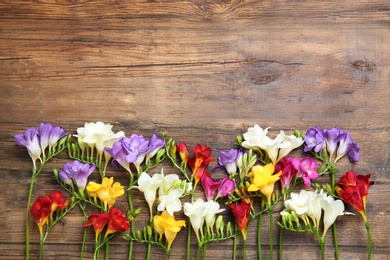 Photo of Beautiful freesia flowers on wooden background